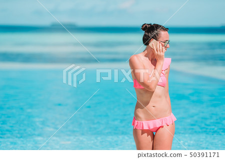 Young beautiful woman talking by phone on white beach 50391171