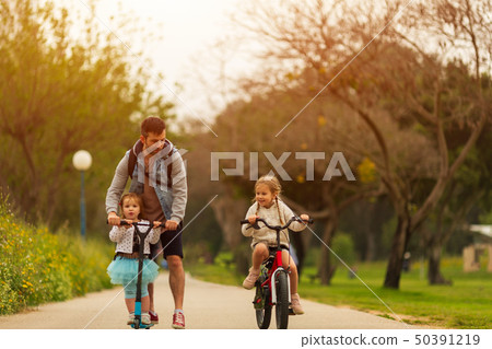 Father and daughters spending time together in park Father and daughters spending time together in park 50391219