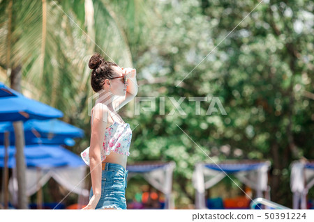 Beautiful young girl relaxing near the swimming pool 50391224