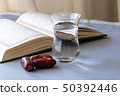 Still life Organic dried dates, cup of drinking water and quran book. Ramadan concept. Selective 50392446