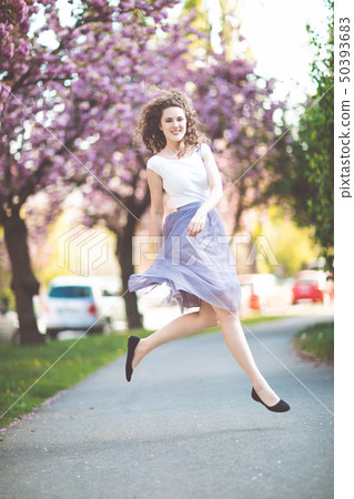 Young girl dancing and jumping on a street, spring 50393683