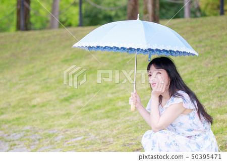 拿著一把藍色傘的一件花服的婦女 50395471