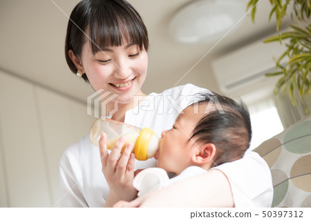 Mother making baby drink milk with baby bottle 50397312
