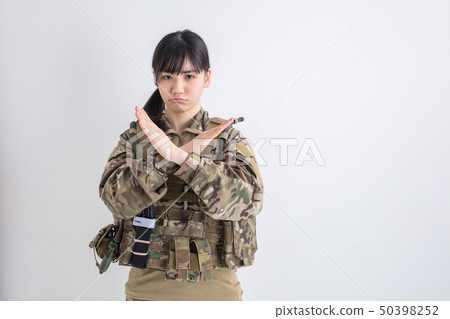 Girl in a camouflage outfit on a white background is a survival game showing smiling with a hand with a smile 50398252