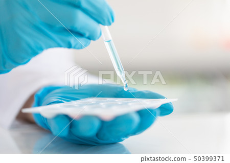 Scientist dropping liquid to sample tray.. 50399371