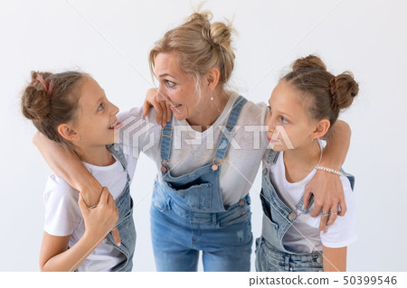Family, sisters and love concept - Mother hugging two twin daughters over white background Family, sisters and love concept - Mother hugging two twin daughters over white background 50399546