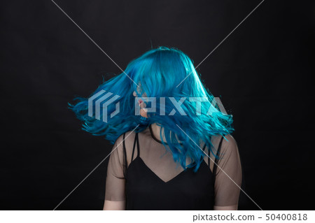 Style and fashion concept - Young and attractive woman with blue hair posing over black background Style and fashion concept - Young and attractive woman with blue hair posing over black background 50400818