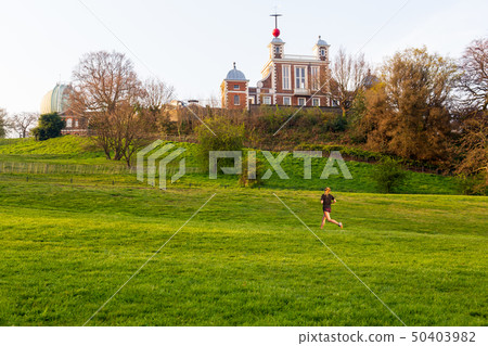 Woman jogging in park with greenwich mean time in background. 50403982