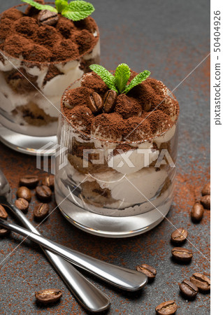 two portions Classic tiramisu dessert in a glass on dark concrete background two portions Classic tiramisu dessert in a glass on dark concrete background 50404926