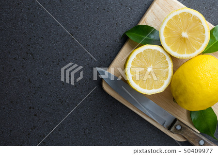 The lemons are on top of wood cutting board The lemons are on top of wood cutting board 50409977