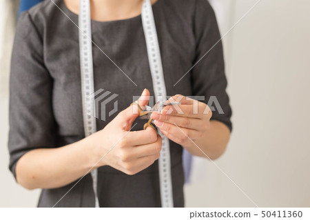 Dressmaker, fashion designer and tailor concept - Seamstress and her hands close up in workshop Dressmaker, fashion designer and tailor concept - Seamstress and her hands close up in workshop 50411360