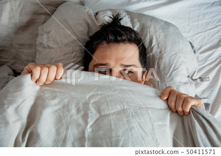 Yound man wake up in a bed at home.  50411571