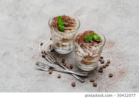 two portions Classic tiramisu dessert in a glass on concrete background 50412077