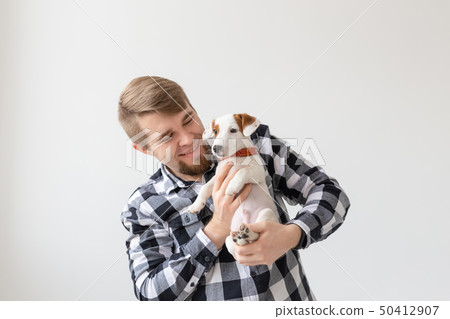 people, pets and dogs concept - young man hugging funny puppy on white background people, pets and dogs concept - young man hugging funny puppy on white background 50412907