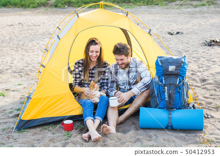 Pet, summer tourism and nature concept - young couple sitting with cat near a tent Pet, summer tourism and nature concept - young couple sitting with cat near a tent 50412953