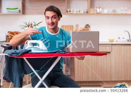 Young man husband doing clothing ironing at home Young man husband doing clothing ironing at home 50413266