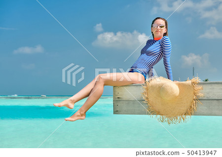 Woman sitting at beach jetty Woman sitting at beach jetty 50413947