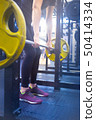 woman with a barbell doing exercises in the gym 50414334