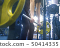 woman with a barbell doing exercises in the gym 50414335