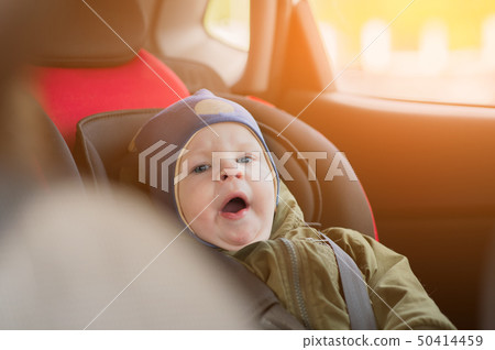 Close Up caucasian cute baby boy woke up and yawns in modern car seat. Child traveling safety on the Close Up caucasian cute baby boy woke up and yawns in modern car seat. Child traveling safety on the 50414459