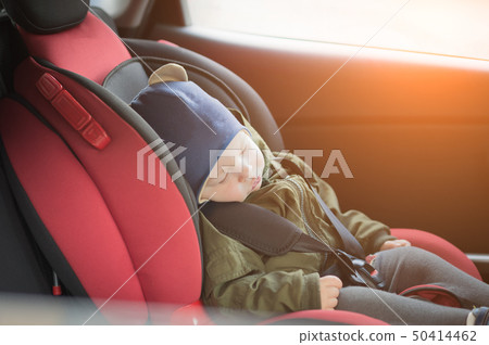 Close Up caucasian cute baby boy sleeping in modern car seat. Child traveling safety on the road 50414462
