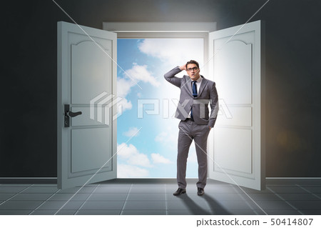 Puzzled businessman in front of big door Puzzled businessman in front of big door 50414807