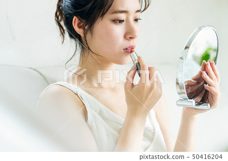 A woman wearing makeup with a table mirror A woman wearing makeup with a table mirror 50416204