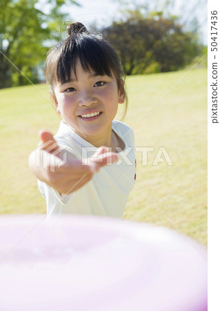 Elementary school girl throwing frisbee in the park 50417436
