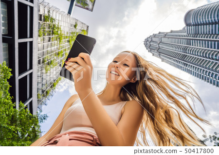 woman using map app on smartphone on the background of skyscrapers woman using map app on smartphone on the background of skyscrapers 50417800