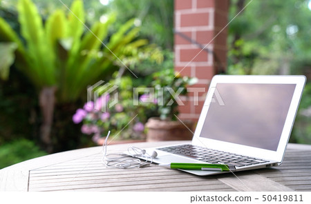 Laptop with ear phones, garden background Laptop with ear phones, garden background 50419811