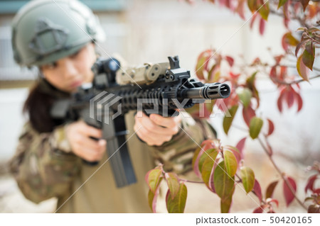 穿著迷彩制服的女孩玩與氣槍的生存比賽 50420165