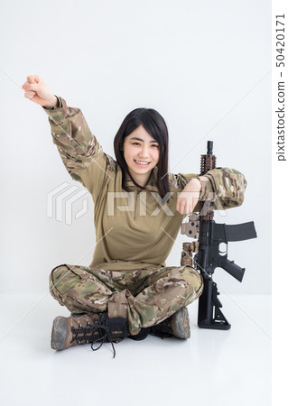 在白色背景上穿著迷彩服裝並且有一把氣槍的女孩也在製作膽量姿勢 50420171