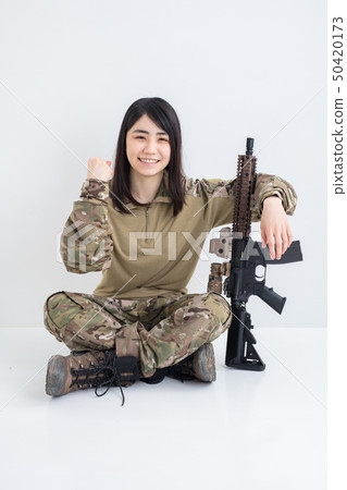 在白色背景上穿著迷彩服裝並且有一把氣槍的女孩也在製作膽量姿勢 50420173