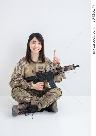 指向有airsoft的微笑的女孩穿在白色背景的偽裝成套裝備 50420177