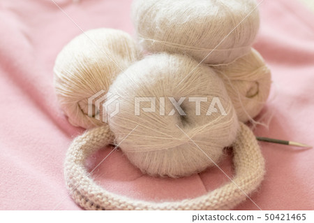 A coil of soft beige wool for knitting on a pink background A coil of soft beige wool for knitting on a pink background 50421465