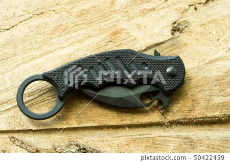 Tactical knife in a folded position on a wooden. Tactical knife in a folded position on a wooden. 50422459