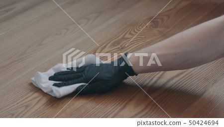 Closeup man in gloves cleaning ash wood floor with wet cloth Closeup man in gloves cleaning ash wood floor with wet cloth 50424694
