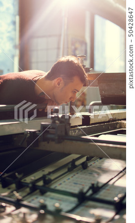 Man controls wide industrial printer in workshop Man controls wide industrial printer in workshop 50428647