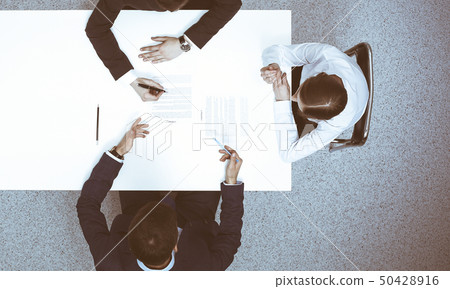 Group of business people and lawyer discussing contract papers sitting at the table, view from above Group of business people and lawyer discussing contract papers sitting at the table, view from above 50428916