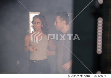 Sexy beautiful dancing kizomba with her partner in a dancing room with smoke Sexy beautiful dancing kizomba with her partner in a dancing room with smoke 50428918