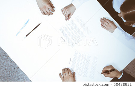 Group of business people and lawyer discussing contract papers sitting at the table, view from above Group of business people and lawyer discussing contract papers sitting at the table, view from above 50428931