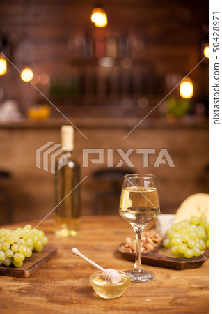 Cheese plate served with a glass of white and wolnuts in a vintage restaurant over a wooden table Cheese plate served with a glass of white and wolnuts in a vintage restaurant over a wooden table 50428971