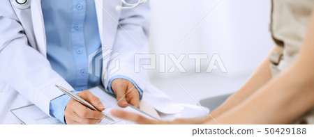Doctor and patient talking. Physician at work in hospital while writing up medication history Doctor and patient talking. Physician at work in hospital while writing up medication history 50429188
