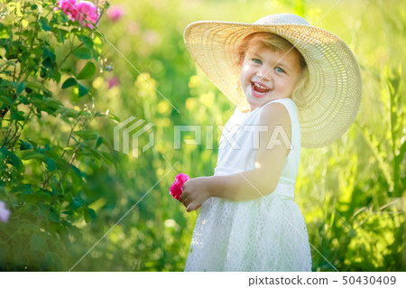A little girl wearing flower yellow dress with white hat and stand in the yellow flower field of A little girl wearing flower yellow dress with white hat and stand in the yellow flower field of 50430409