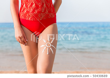 Sun shape is made of sunscreen on woman's leg at 50430689
