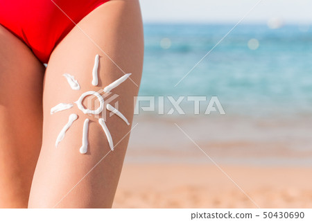 Sun shape is made of sunscreen on woman's leg at 50430690