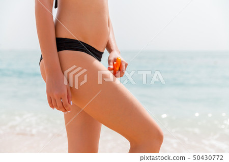 Young girl is applying sunblock form the spray on Young girl is applying sunblock form the spray on 50430772