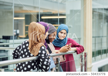 Group of islamic women of different ethnicity watching on the phone together Group of islamic women of different ethnicity watching on the phone together 50433778