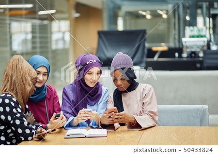 Arabian young women watching on cellphone musical video clip standing together. 50433824