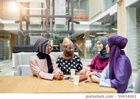 Muslim young women of diverse ethnicity talking about new book of famous author Muslim young women of diverse ethnicity talking about new book of famous author 50434061